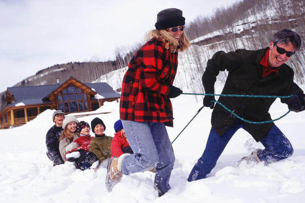 A couple pulling children on a sled