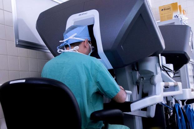 Dr. Samuel Cancel-Rivera, an OB-GYN physician, looks through a 3D imaging system while operating on a patient using the da Vinci Xi surgical system. Army photo