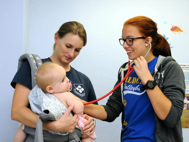 A student assists during a well baby check-up. (U.S. Navy/David D. Underwood, Jr.)