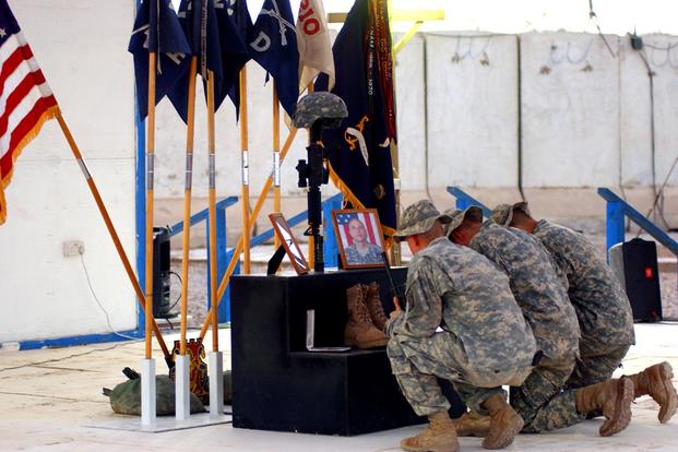 Soldiers kneel to pay their respects to Staff Sgt. Travis Atkins, who was killed June 1 by a suicide bomber near Sadr Al-Yusufiyah, Iraq, at a memorial ceremony held June 7, 2007 at Camp Striker. (U.S. Army/Spc. Chris McCann, 2nd BCT PAO)