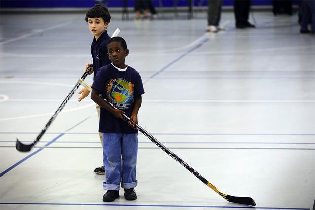 Calvin Stubbs, front, 6, and Alex Parsley, back, 9, stand in line to hit hockey pucks during the Pensacola, Florida Ice Flyers’ visit to the Hurlburt Field youth center. (Air Force/Julianne Showalter)