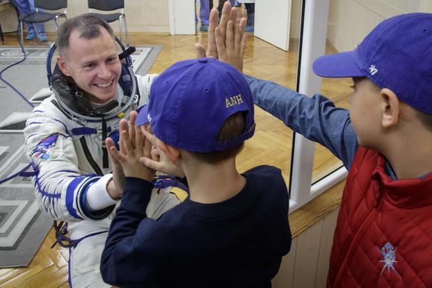 Air Force Col. Nick Hague's sons visit with him through a glass window as he prepares for a trip into space. NASA photo