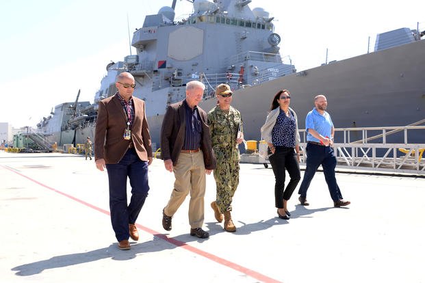 Five people walk next to a ship. (U.S. Navy/Rick Naystatt)