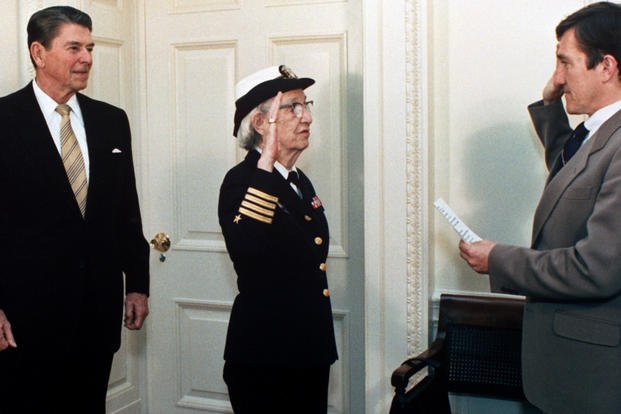 Secretary of the Navy John Lehman promotes Capt. Grace Hopper to the rank of commodore in a ceremony at the White House. President Ronald Reagan is at the left. (White House photo)