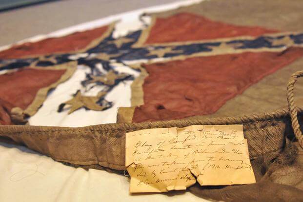 A Confederate flag captured from the CSS Hampton lies on a protective sheet.
