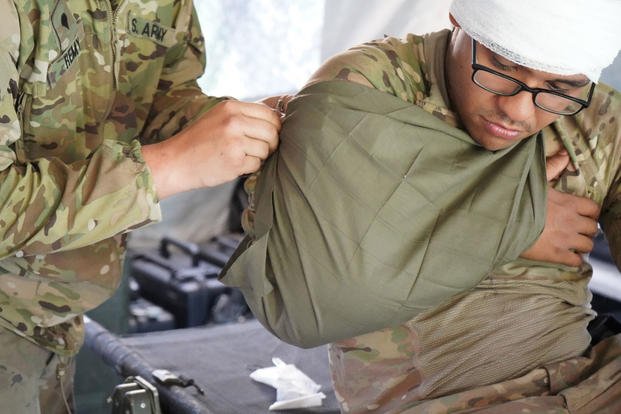Army sling around patient's shoulder medical evacuation rehearsal