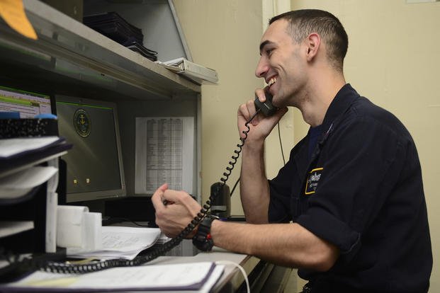 A U.S. Navy counselor first class speaks to a sailor about their career over the phone aboard the aircraft carrier USS Nimitz.