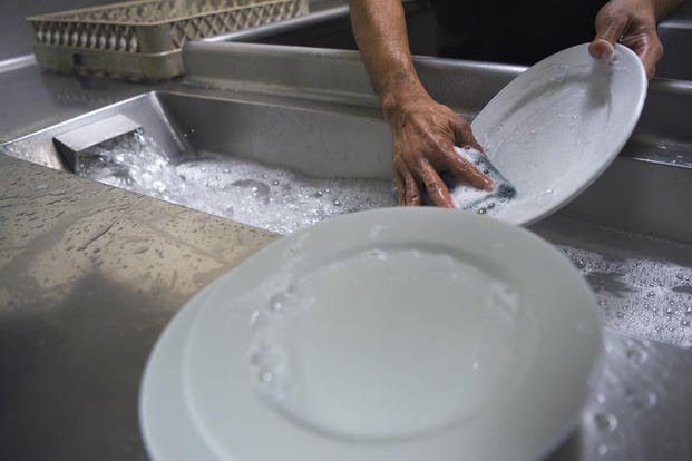 A civilian kitchen worker washes plates at the Riptide Dining Facility at Hurlburt Field, Florida.
