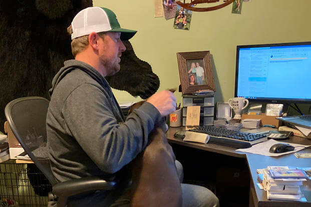 Steve Stauff pets his German shorthaired pointer, Beatrice, while working from home.