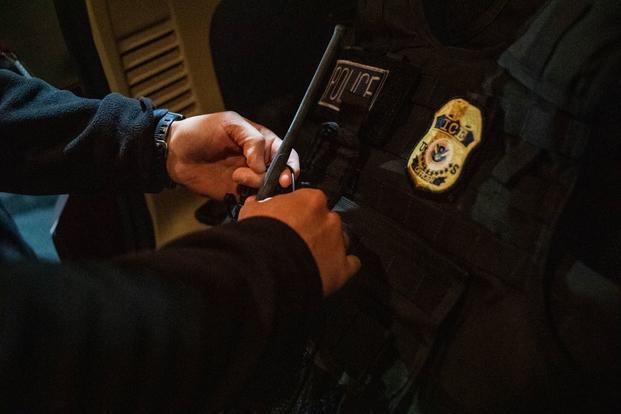 Close up of U.S. Immigration and Customs Enforcement officer preparing his equipment.