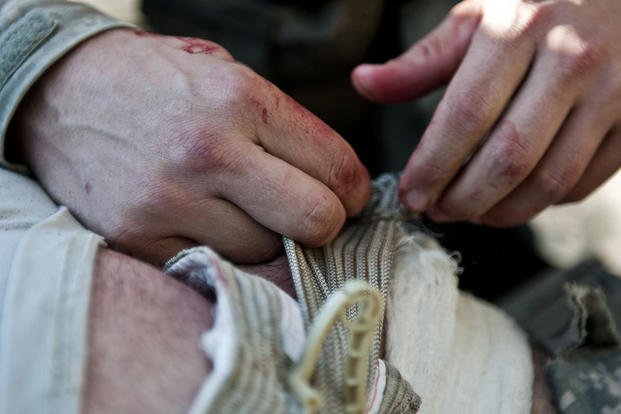 U.S. Army Spc. Brit B. Jacobs, a combat medic, bandages a wounded soldier in the Shal Valley in eastern Afghanistan's Nuristan Province.
