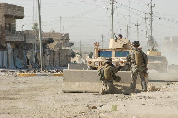 Two Paratroopers from Company A, 2nd Battalion, 325th Airborne Infantry Regiment, 82nd Airborne Division watch as two HMMWVs pass their patrol on a street in Tall Afar, Iraq. 