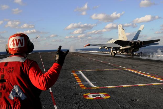 A sailor signals as an F/A-18C Hornet takes off on the flight deck aboard the aircraft carrier USS George H.W. Bush on Dec. 2, 2016, in the Atlantic Ocean. (U.S. Navy photo/Brooke Macchietto)