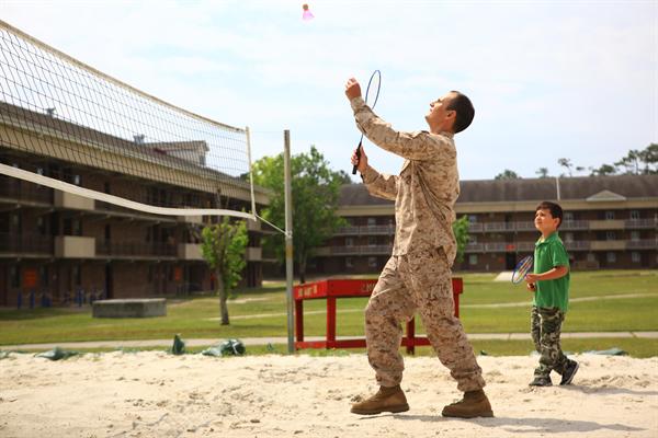 Servicemember and child playing badminton.