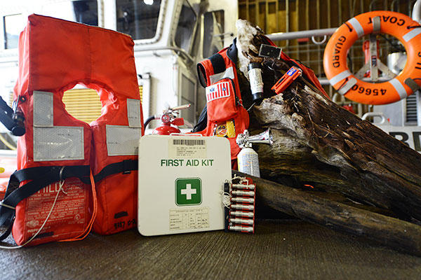 Key pieces of boating safety equipment, including a lifejacket, a first aid kit, a fire extinguisher, and visual distress signals. The Coast Guard urges boaters to carry survival gear like this. (U.S. Coast Guard/Seaman Sarah Wilson)