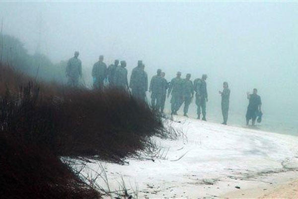 Military personnel wade in the water and search on the beach under heavy fog at Eglin Air Force Base, Fla., Wednesday, March 11, 2015, for the wreckage of a military helicopter that crashed with 11 service members aboard. (AP Photo/Melissa Nelson-Gabriel)