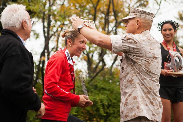 Marine Corps Capt. Christine Taranto, the silver female finisher of the 40th Marine Corps Marathon, accepts her wreath from Gen. Robert Neller, the 37th Commandant of the Marine Corps, in Arlington, Virginia, Oct. 25. (Photo By: Sgt. Justin M. Boling)