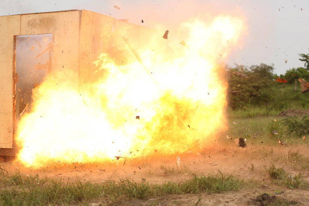 A Uganda's People Defense Force soldier detonates an oval charge on the wall of a notional objective position of desired entry while the team seeks cover around the corner of the position at Camp Singo, Uganda Nov. 25, 2015. (Photo: Cpl. Olivia McDonald)