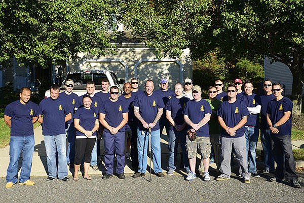 Coast Guard Chief Warrant Officer Richard Sambenedetto poses outside his home in New Jersey with 20 prospective chief petty officers who helped him out with landscaping and housework. (U.S. Coast Guard/Chief Petty Officer Nick Ameen)