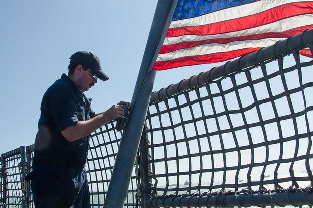 Aviation Machinist's Mate 1st Class Sean Wilde raises the colors aboard USS Fort Worth after the ship moored to the pier in Phuket, Thailand for a scheduled port visit. (Photo: Mass Communication Specialist 2nd Class Antonio Turretto Ramos)