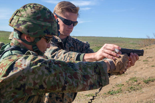 Marine Corps Sgt. Mason Wilhelmy assists a soldier of the Japan Ground Self-Defense Force’s Western Army Infantry Regiment’s Scout Sniper program with proper pistol grip during an abbreviated scout sniper course. (Photo: Lance Cpl. Timothy Valero)