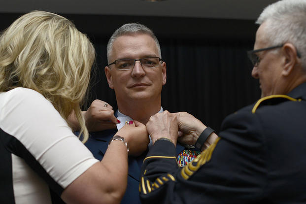 Janelle Terry and Army 1st Sgt. (retired) Jerry Loya pin new collar devices onto the uniform of Wilton Terry as he is advanced from petty officer first class to chief petty officer. (U.S. Coast Guard/CPO Nick Ameen)