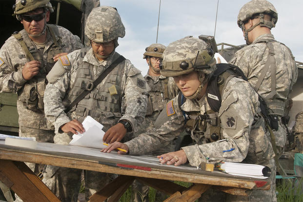 1st Lt. Kayla Christopher, fire direction officer, works with fellow officers to calculate distance and trajectories to targets while planning a fire mission for the battery during training at Fort Riley, Kansas. (U.S. Army/Sgt. Anthony Jones)