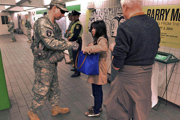 An Army National Guard member searches the bag of a woman as she entered an MBTA subway station near Boston Common, one day after a pair of bombs exploded at the finish line of the Boston Marathon.
