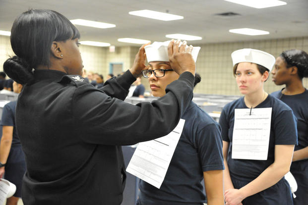 Engineman 2nd Class Shanice Floyd, a recruit division commander, ensures the proper fit of Seaman Recruit Megan Marte's white enlisted hat, or "Dixie cup," during uniform issue at Recruit Training Command. Sue Krawczyk/Navy