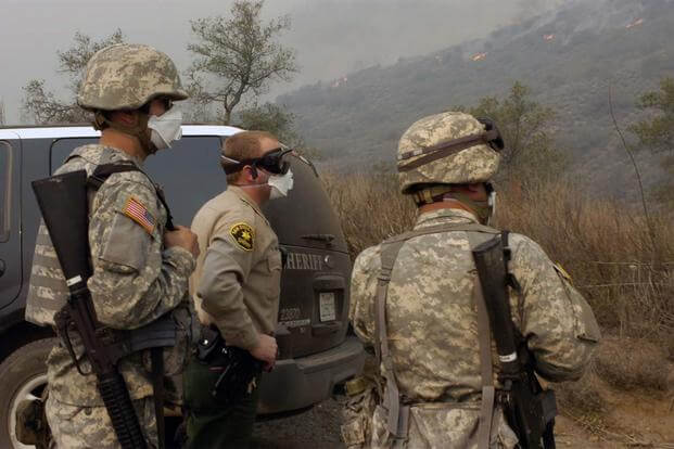 California National Guard Soldiers flank Deputy Todd Viller of the San Diego County Sheriff's Office as the three monitor progress of a wildfire near Valley Center, Calif. (Photo Credit: Staff Sgt. Jim Greenhill)