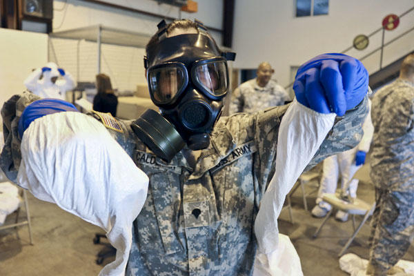 Army Spc. Kristal Calderon practices donning and removing protective equipment and a mask after a class at the logistical warehouse on Fort Gordon, Ga., Oct. 14, 2014. DoD photo