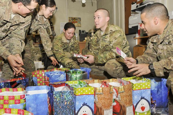 Service members gather around Christmas presents.