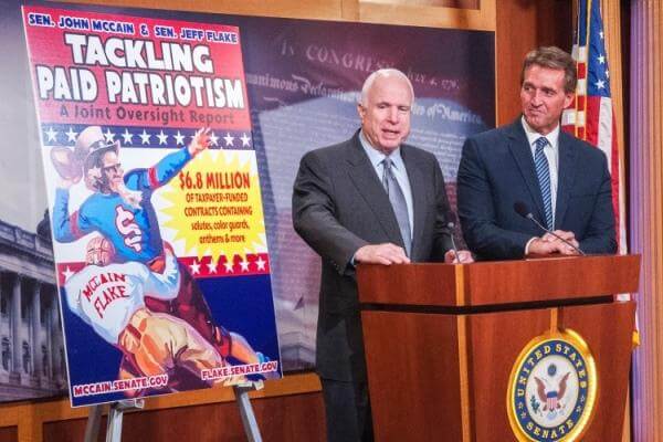 Sens. John McCain and Jeff Flake of Arizona during a press event on Capitol Hill on Wednesday, Nov. 4, 2015, stand beside a billboard touting the results of a report questioning a Pentagon program that doles out millions of dollars to professional sports 