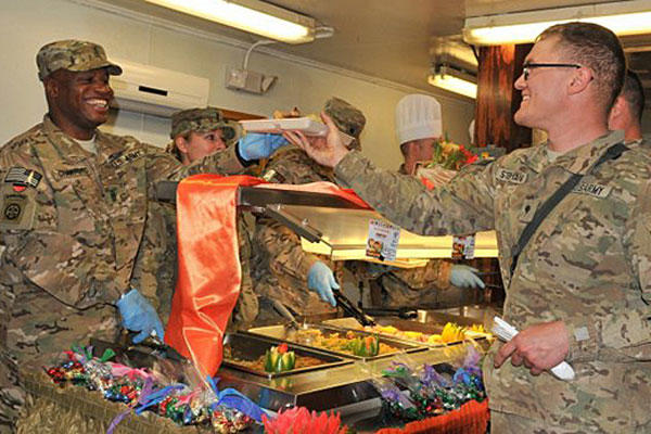 Command Sgt. Maj. Christopher T. Crawford gives Spc. Victor W. Stephans his food while serving lunch at the Koele Dining Facility on Thanksgiving Day, Nov. 28, 2013, at Bagram Air Field, Afghanistan. Sgt. Sinthia Rosario/Army