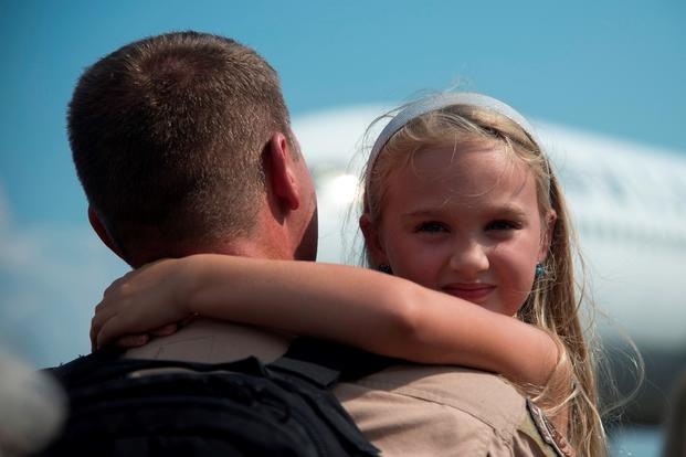A girl smiles as she hugs her father during the return of the 17th Airlift Squadron on Sept. 4, 2013, at Joint Base Charleston Air Base, S.C. (U.S. Air Force photo/Rasheen Douglas)