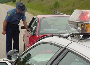 A highway patrol officer stops a red car.