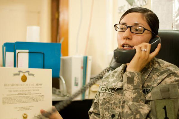 An Army human resources worker answers a call at her desk.