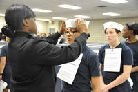 Engineman 2nd Class Shanice Floyd, a recruit division commander, ensures the proper fit of Seaman Recruit Megan Marte's white enlisted hat, or &quot;Dixie cup,&quot; during uniform issue at Recruit Training Command. Sue Krawczyk/Navy