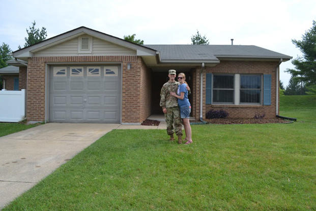 Military couple in front of home