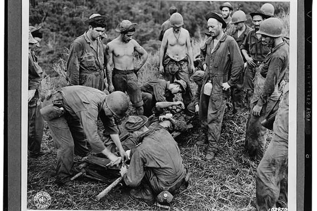 A casualty from the fighting at Guadalcanal is transferred from a makeshift stretcher before being taken through jungle and down river to a field hospital. (Photo courtesy Library of Congress)