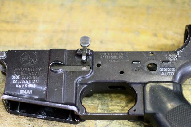 The receiver of a former M4 carbine shows laser etching to reflect it is now an M4A1 capable of firing on full-auto. (U.S. Army)