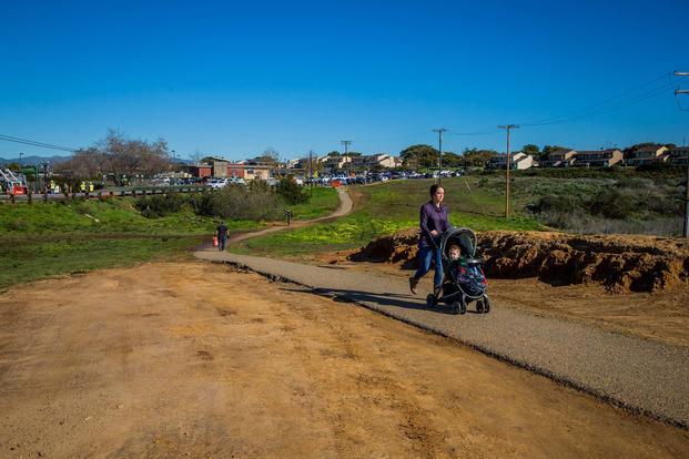 Personnel stationed at Marine Corps Base Camp Pendleton, California, walk on a dirt path around Carnes Road on Feb. 6, 2019. The path was opened to enable foot traffic around the Santa Margarita I and Wire Mountain II housing areas in order to avoid a sinkhole that developed in the road due to erosion. (U.S. Marine Corps photo by Cpl. Juan Bustos)