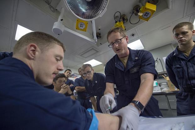 Hospital Corpsman 2nd Class Jeffrey Thorton demonstrates how to insert an intravenous needle during medical training aboard the Whidbey Island-class amphibious dock landing ship USS Fort McHenry (LSD 43). (U.S. Navy/Mass Communication Specialist 3rd Class Chris Roys)