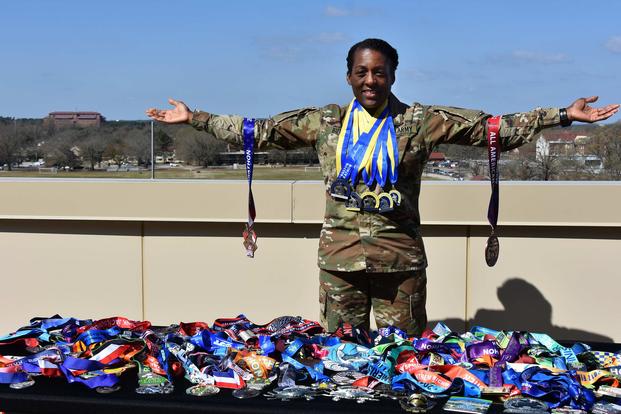 Chief Warrant Officer 4 Beofra K. Butler, administrative executive officer to the commanding general, U.S. Army Forces Command, poses with her marathon medals on March 22, 2019. She has run 99 marathons since 2008. Around her neck are medals from her five previous Boston Marathons. She will run her 100th race April 15 in Boston. (U.S. Army photo by Eve Meinhardt)
