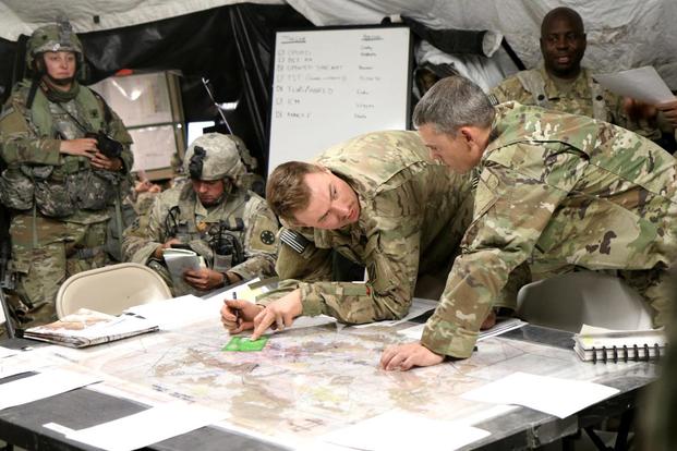 Army Capt. Timothy Cody and Maj. Ritchie Rhodes Jr. discuss operational plans May 6 inside the 2nd Armored Brigade Combat Team’s tactical operations center during a recent rotation at the National Training Center at Fort Irwin, California. Matthew Cox/Military.com