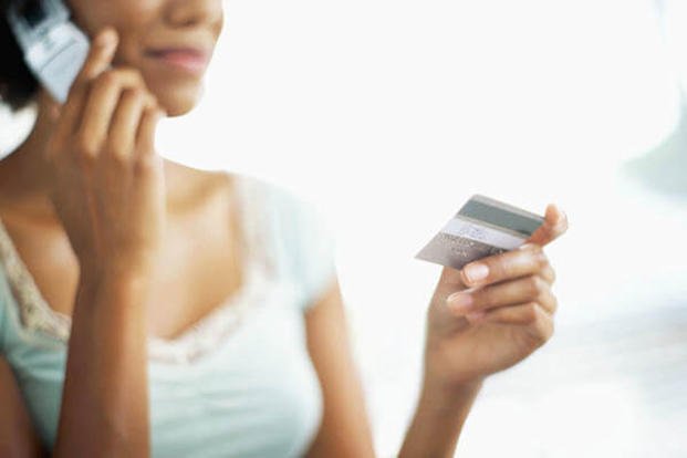 Woman on the phone holding a credit card.