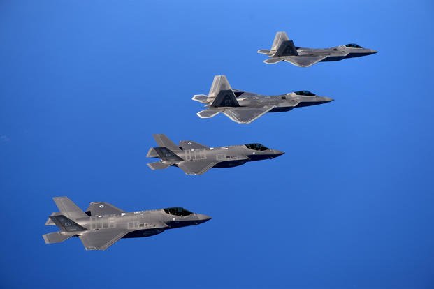 F-22 Raptors and F-35A Lightning IIs fly in formation.