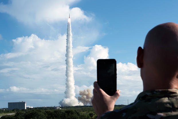 An Airman records the liftoff of a Delta IV GPS III Magellan rocket.