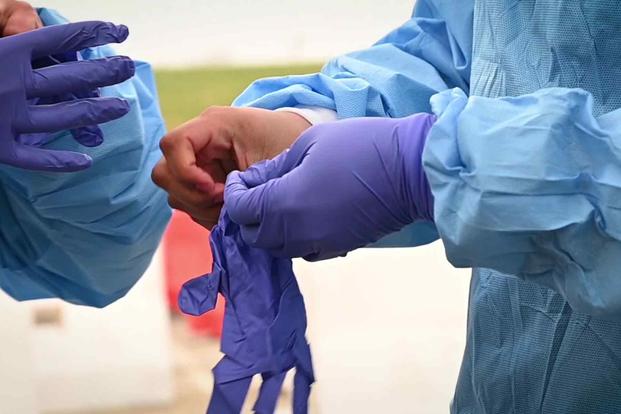 FILE PHOTO -- Medical personnel put on gloves while assisting in the fight against COVID-19. 
