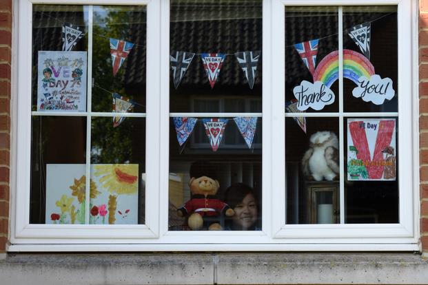 A child of a U.S. Air Force airman displays Victory in Europe Day artwork in their windows of their homes.
